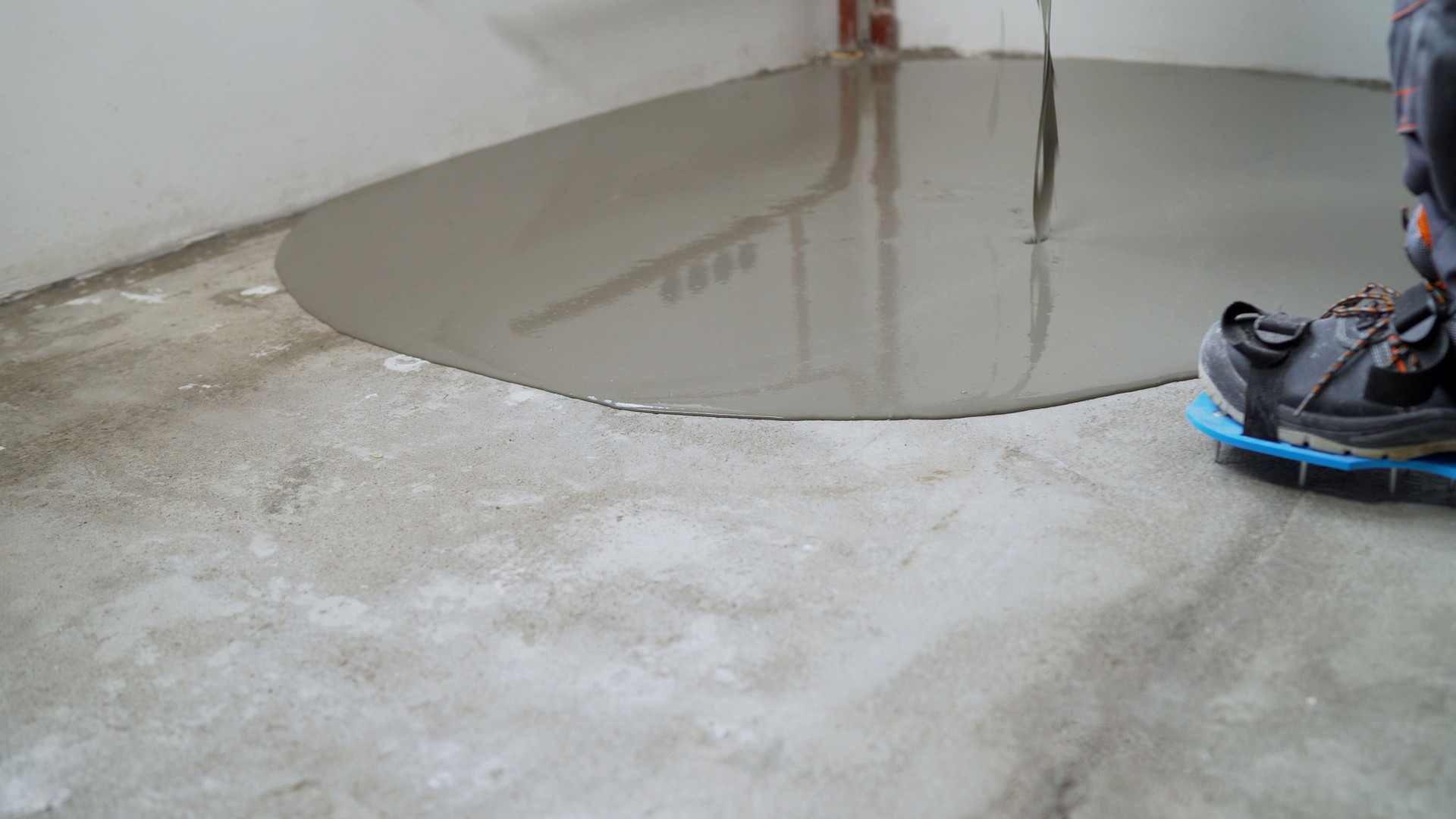 Construction worker pouring self-leveling concrete mix on the floor